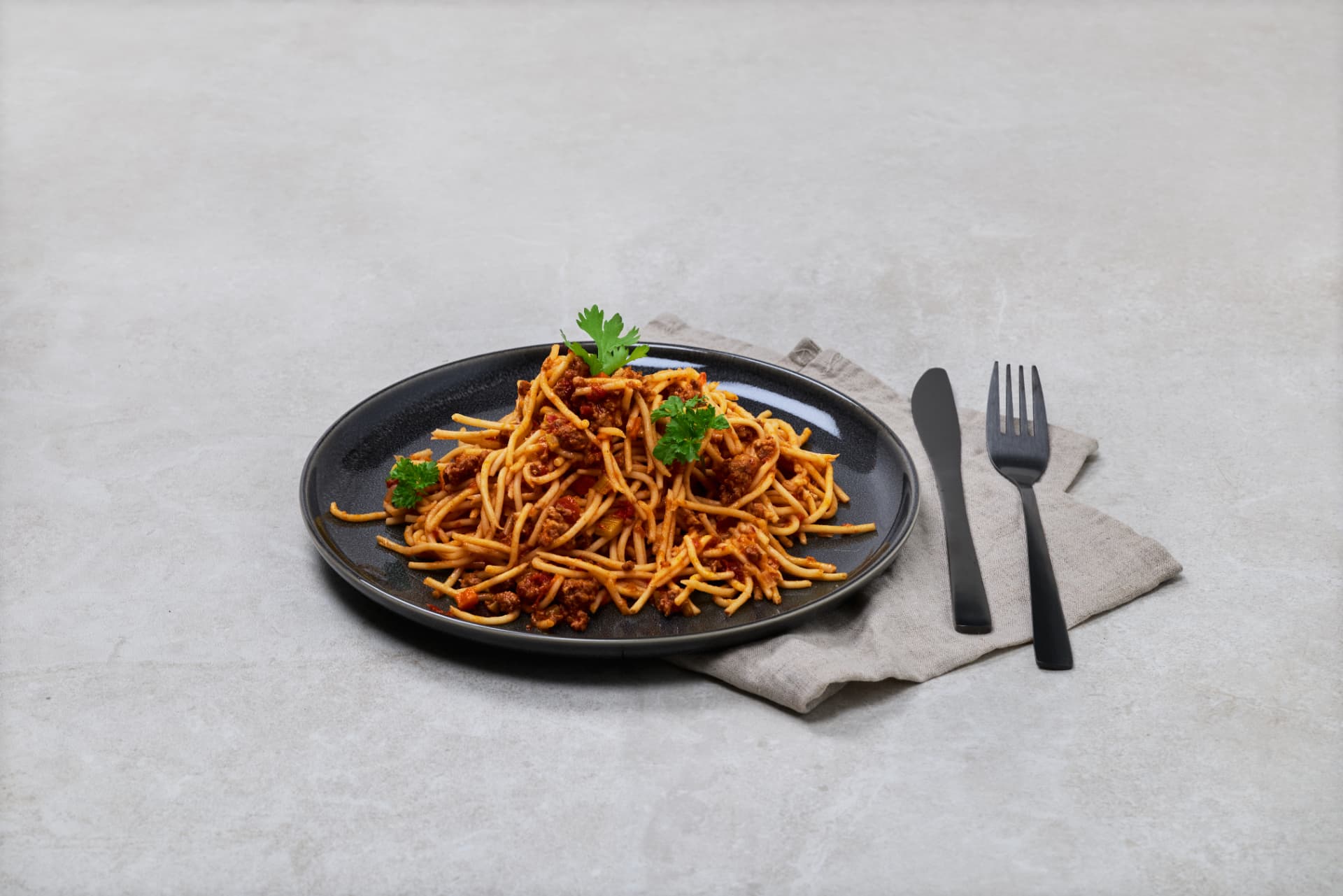 Spaghetti bolognese på svart tallerken med persille