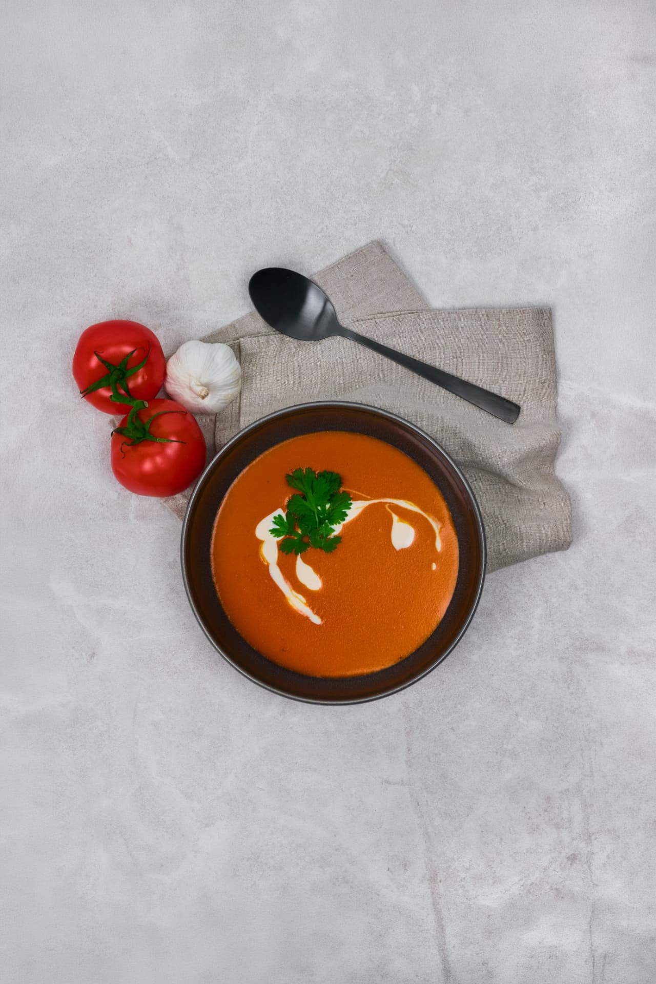 Tomatsuppe fotografert ovanfrå med fløtespiral og ferske tomatar